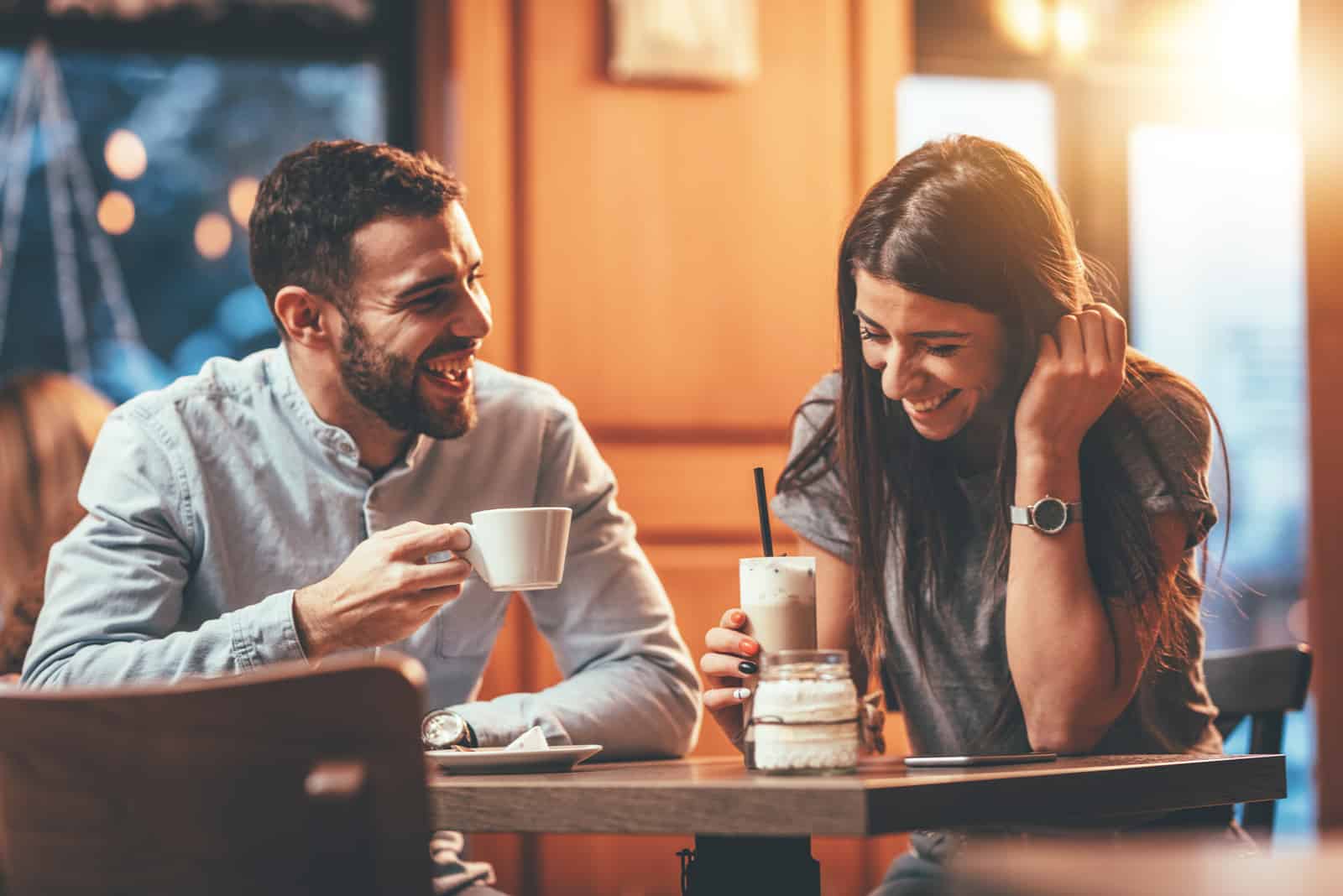 un homme et une femme souriants s'assoient à une table et boivent du café