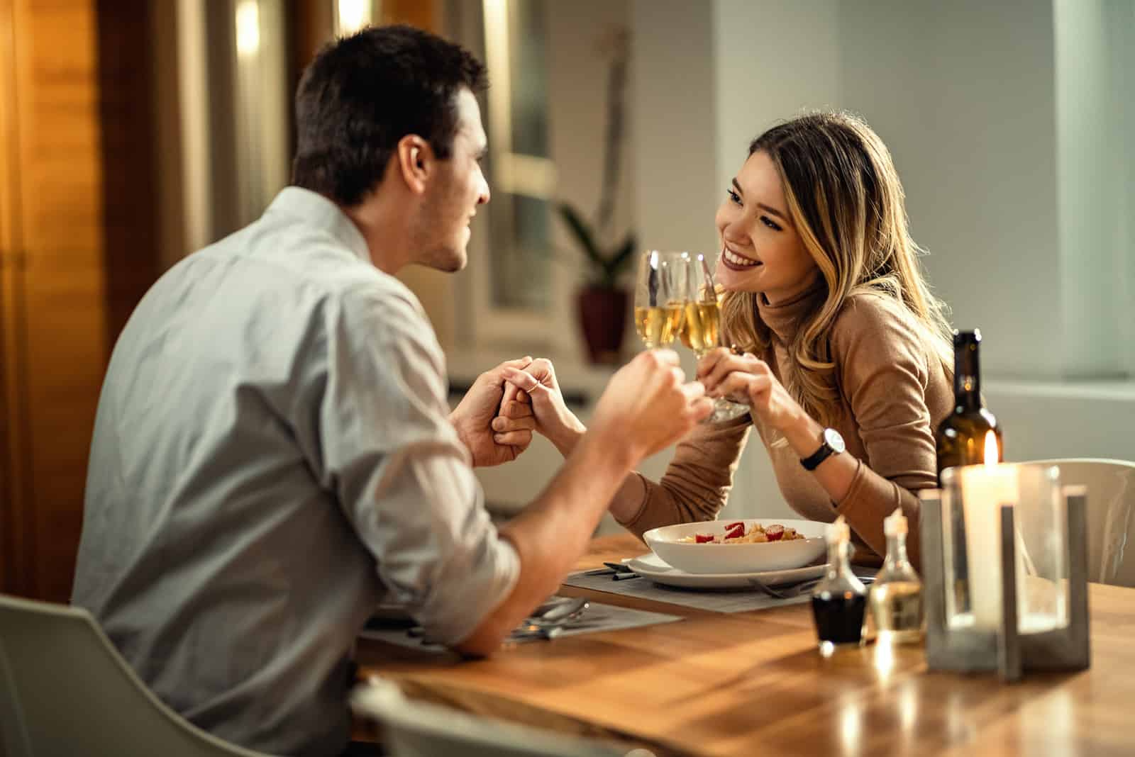 un homme et une femme trinquent avec du vin et se tiennent la main
