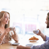 un homme et une femme sont assis à une table en train de boire du café et de parler