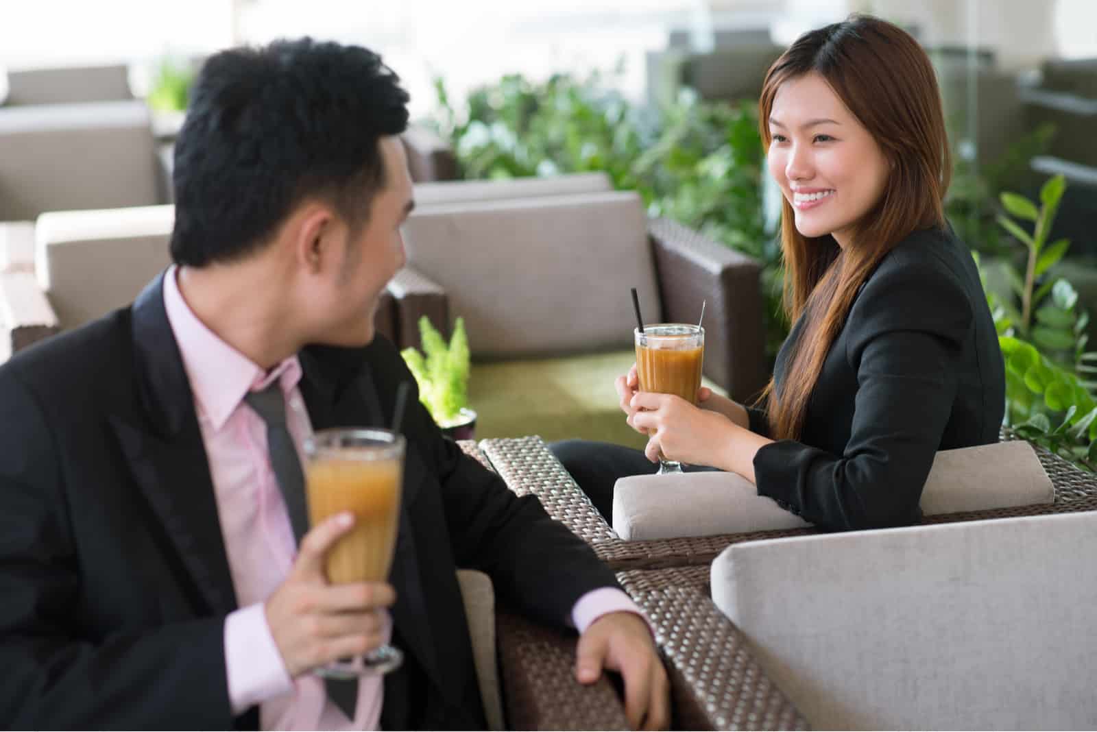 un homme et une femme sont assis dans un café et se regardent 