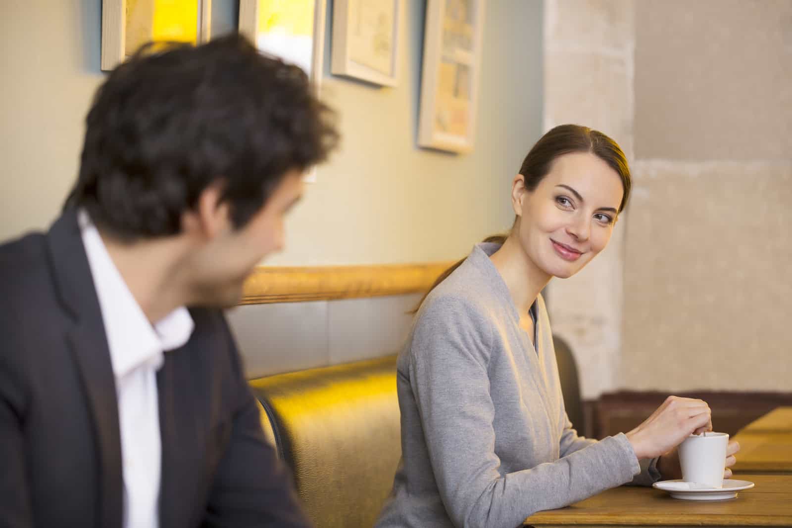 un homme et une femme sont assis dans un café et se regardent