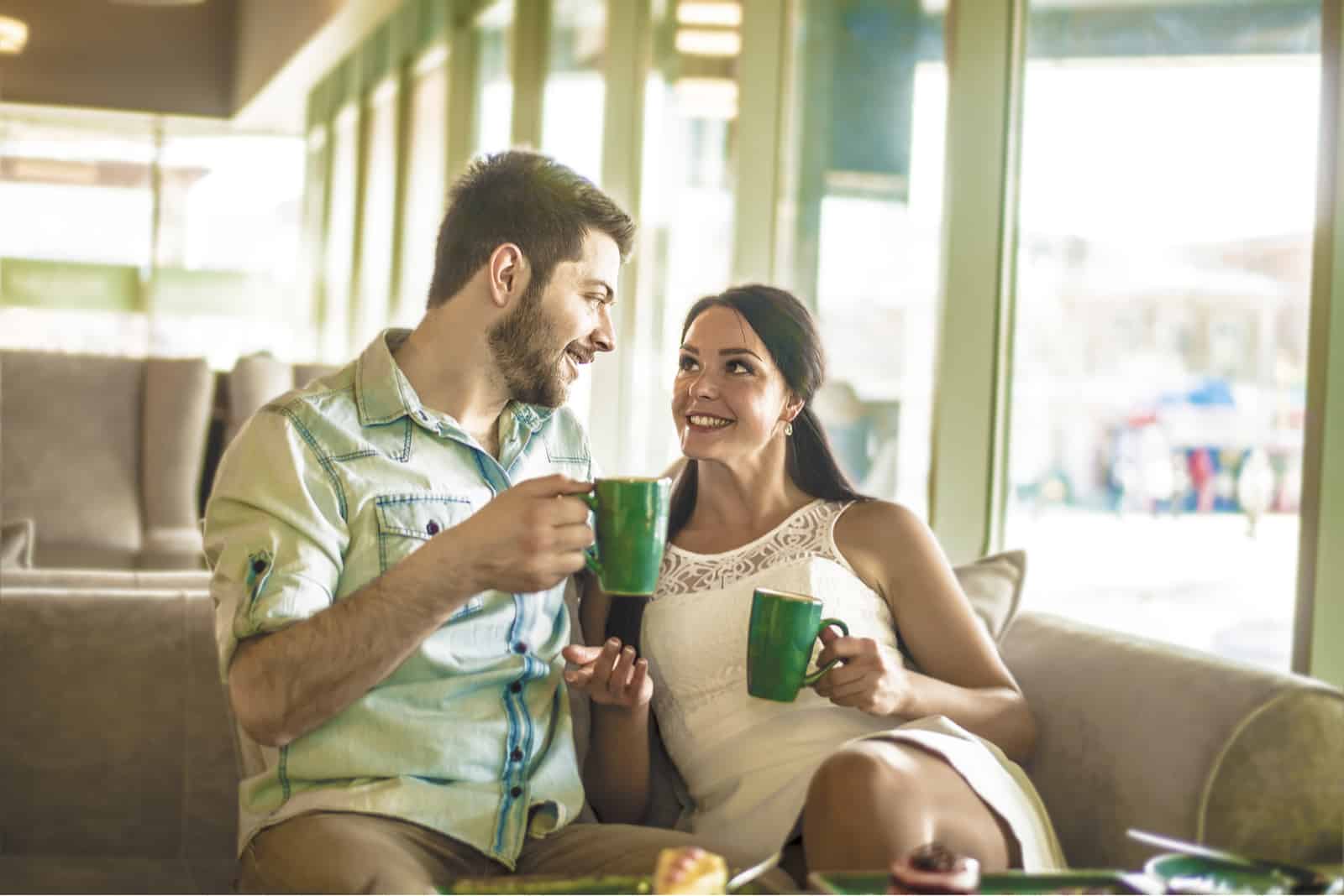 un homme et une femme sont assis en train de boire du café et de parler