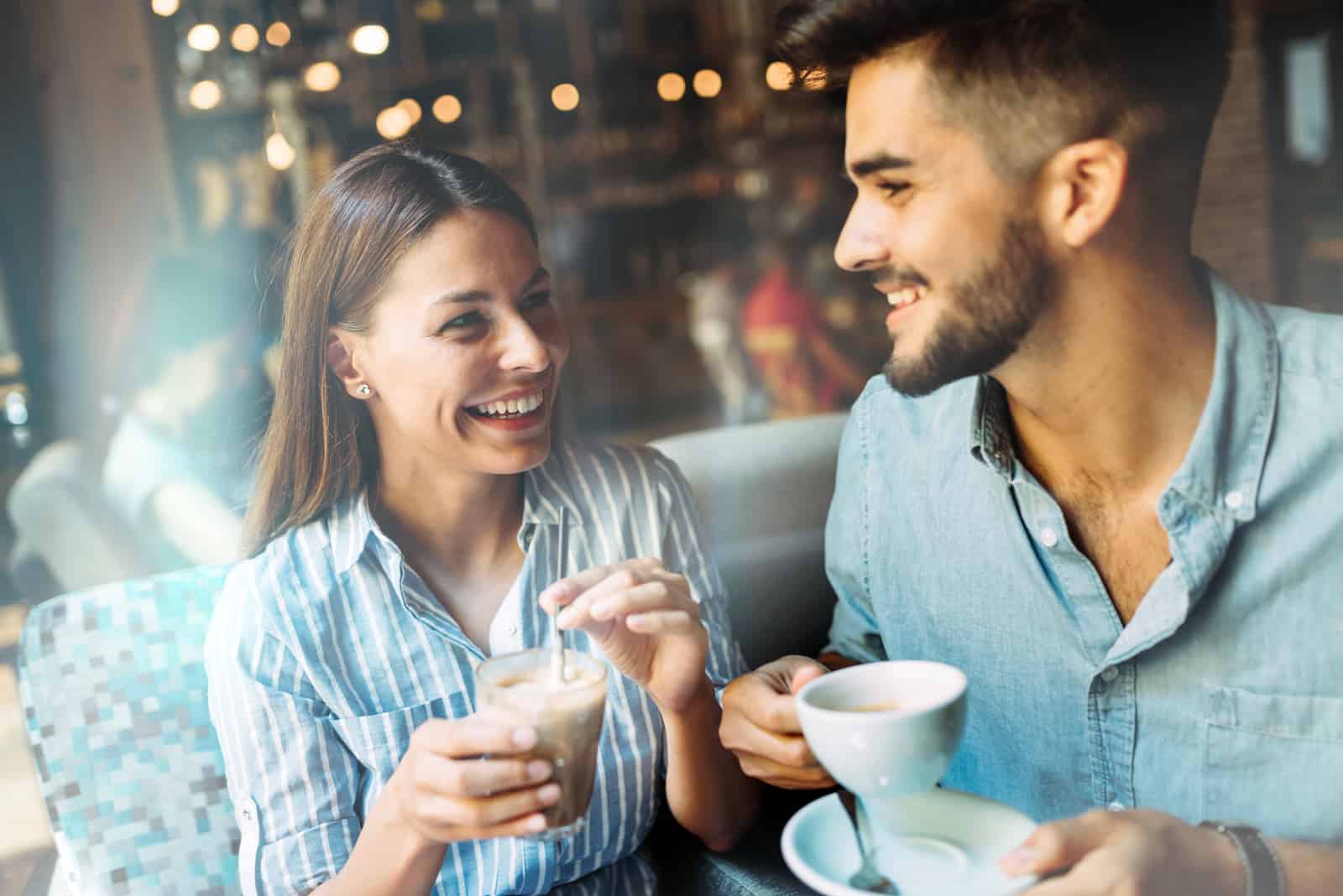 un homme et une femme souriants s'assoient et boivent du café