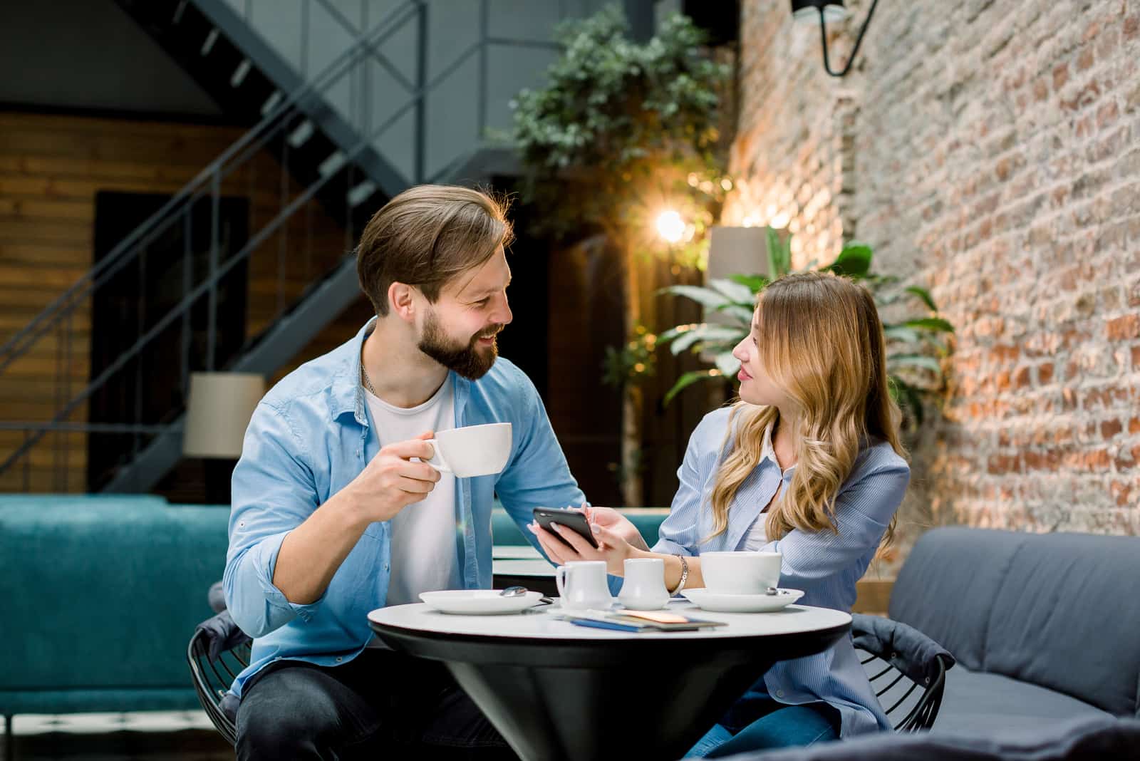 un homme tient une tasse de café à la main et parle à une femme