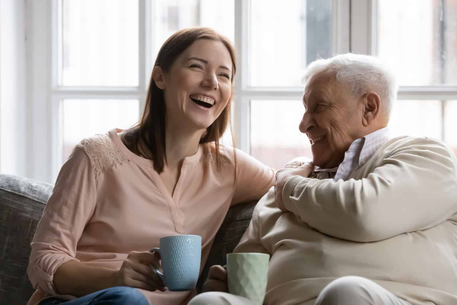 fille et père assis sur le canapé en riant