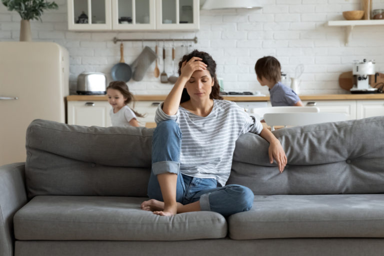 mère tenant sa tête pendant que les enfants courent en arrière-plan