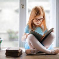 fille au gingembre lisant un livre par la fenêtre