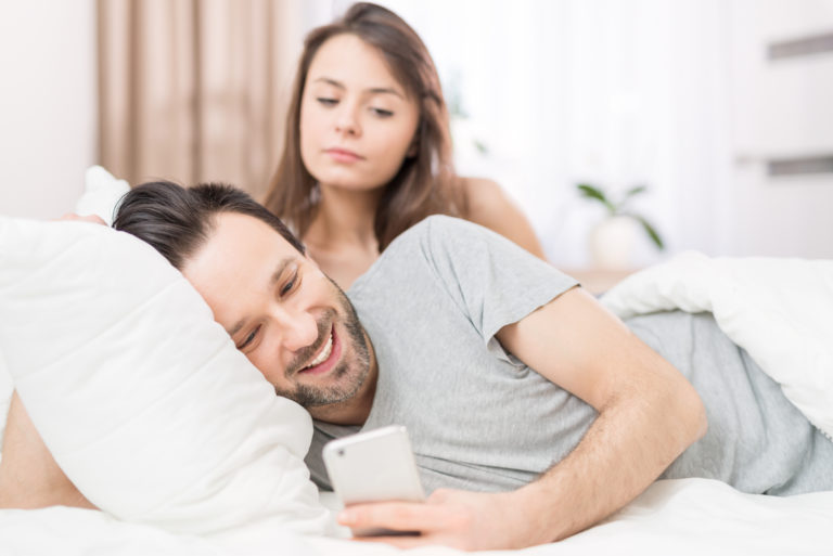 un homme envoie des SMS pendant qu'une femme regarde
