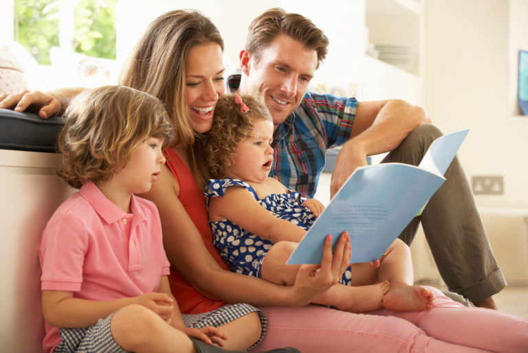 Famille assise sur le sol en lisant un livre