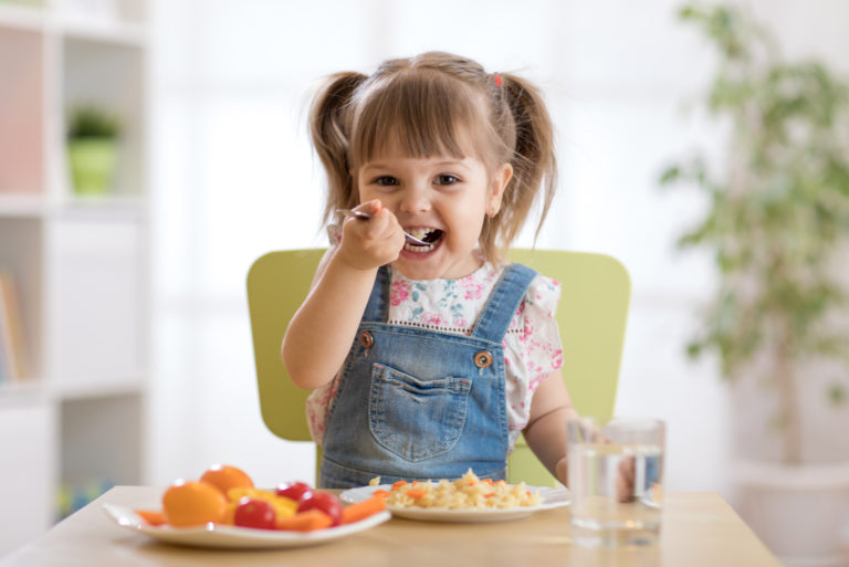 tout-petit mignon assis dans une chaise de bébé en train de manger