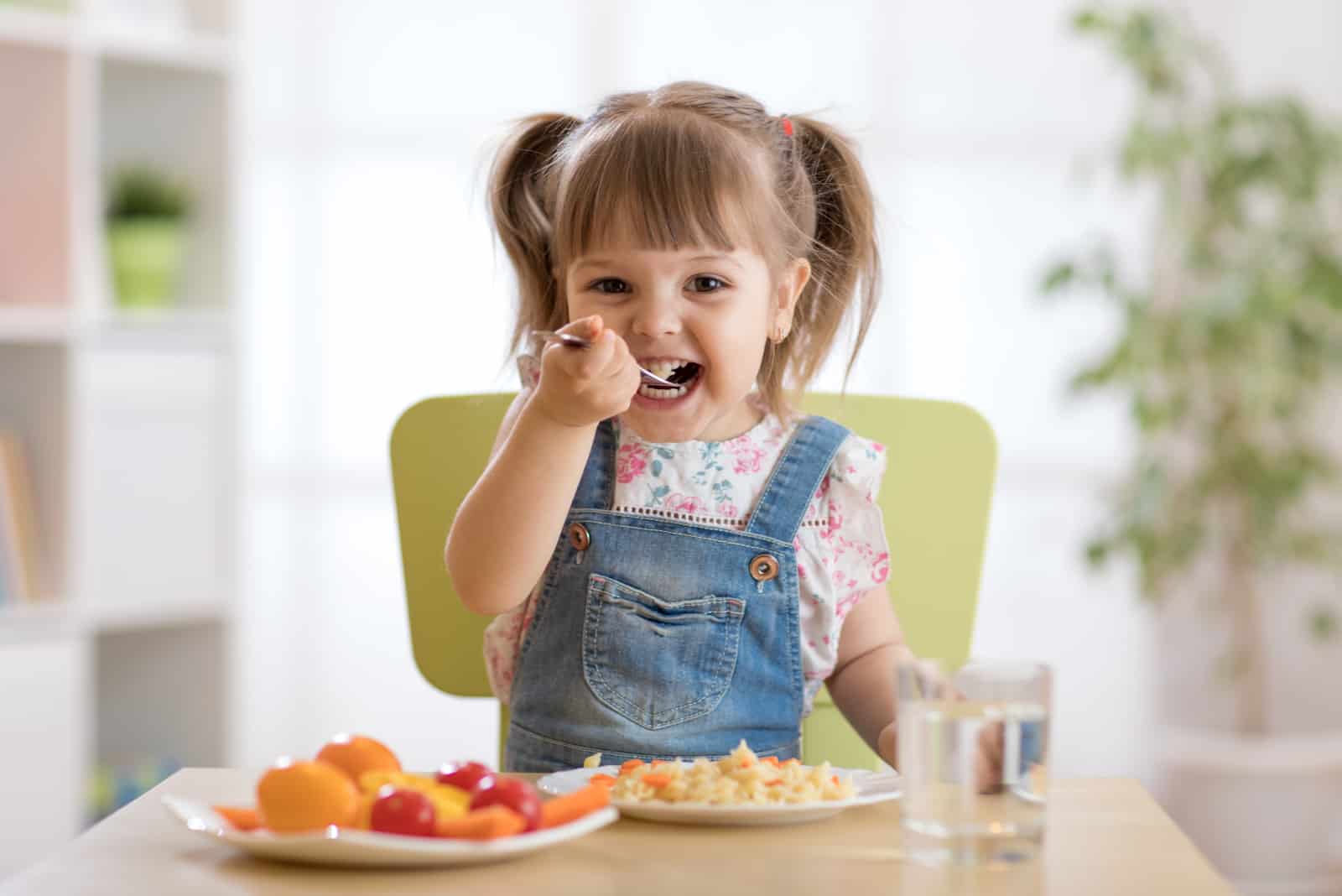tout-petit mignon assis dans une chaise de bébé en train de manger