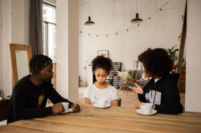 parents discutant avec leur enfant assis dans la salle à manger