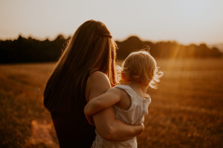 tout-petit regardant dans le coucher du soleil
