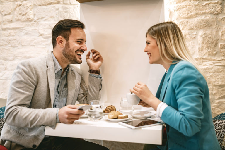 un homme et une femme souriants s'assoient et parlent autour d'un café