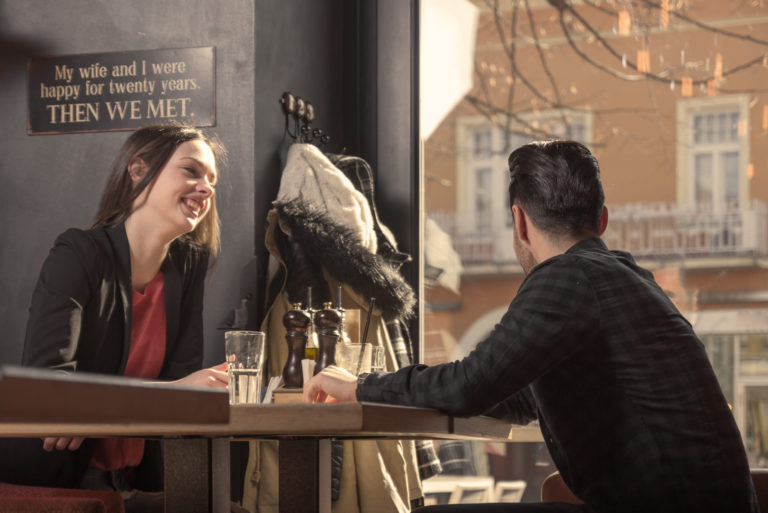 un homme et une femme sont assis à une table pendant qu'il regarde par la fenêtre