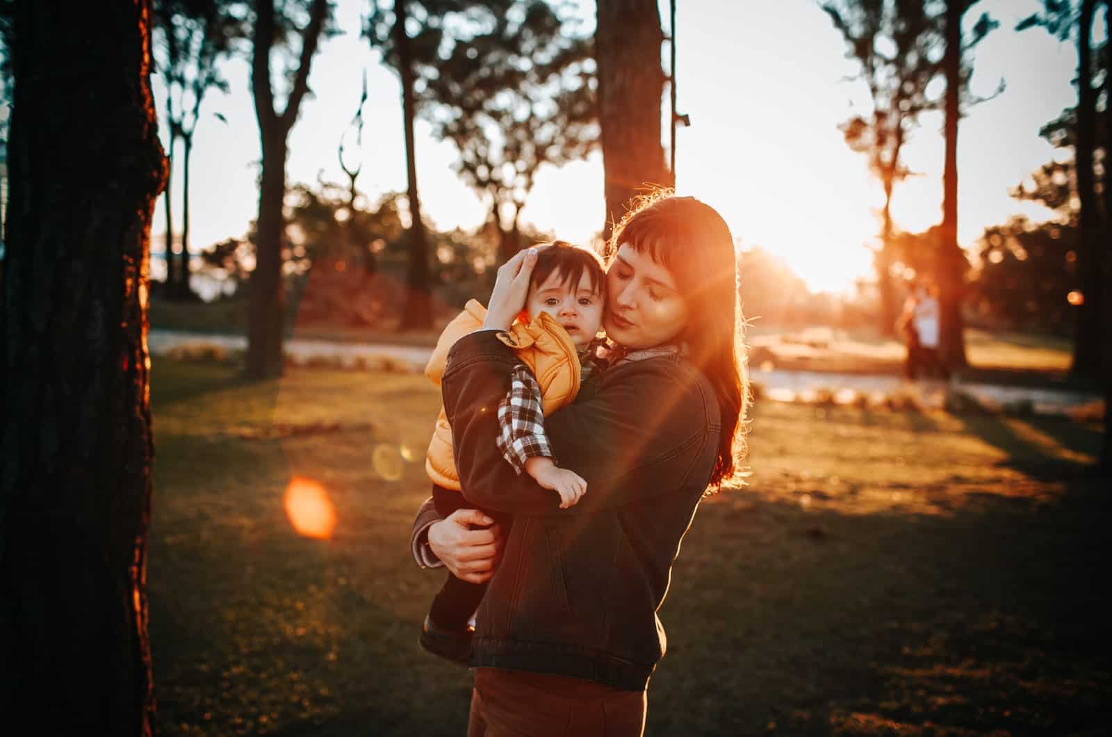 femme étreignant son enfant à l'extérieur dans le parc au coucher du soleil
