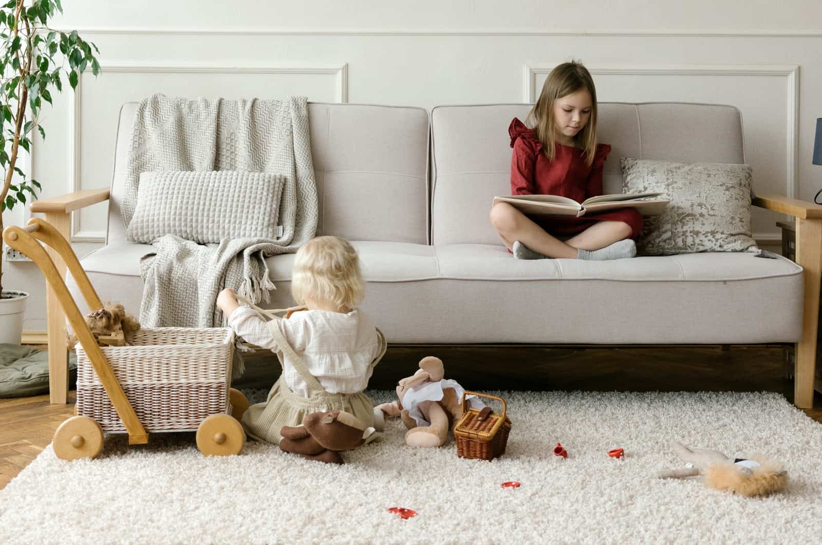 fille lisant sur un canapé pendant que sa sœur joue par terre