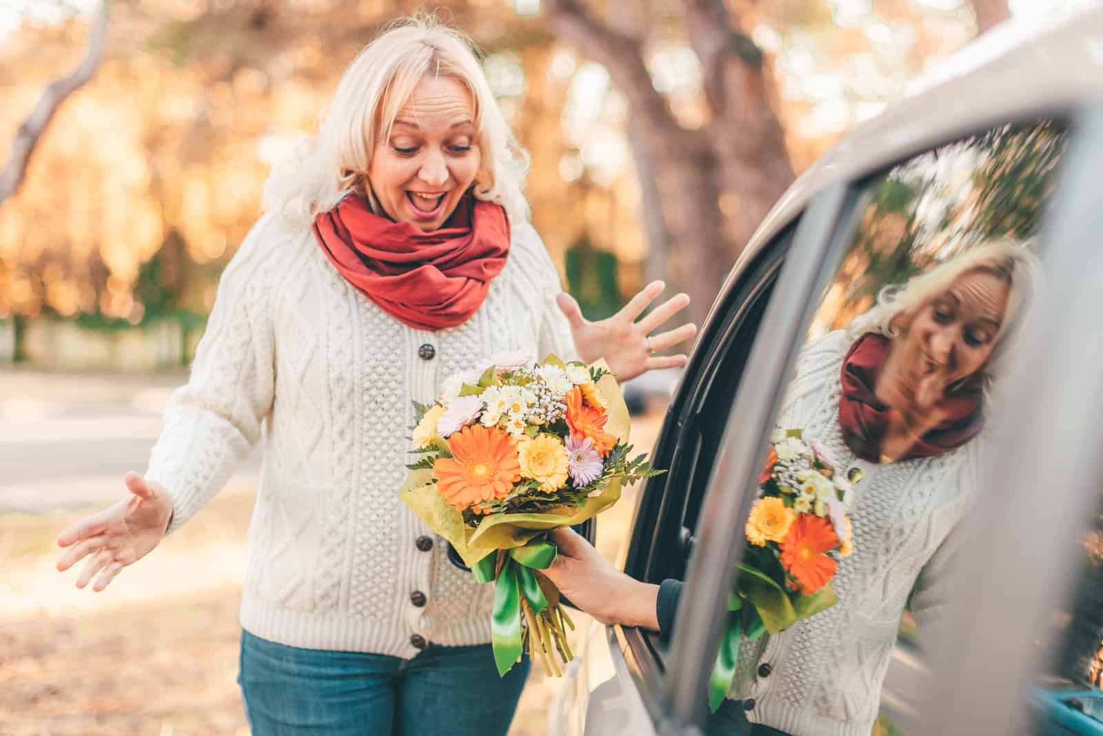 la femme souriante a été surprise par un homme avec un bouquet de roses