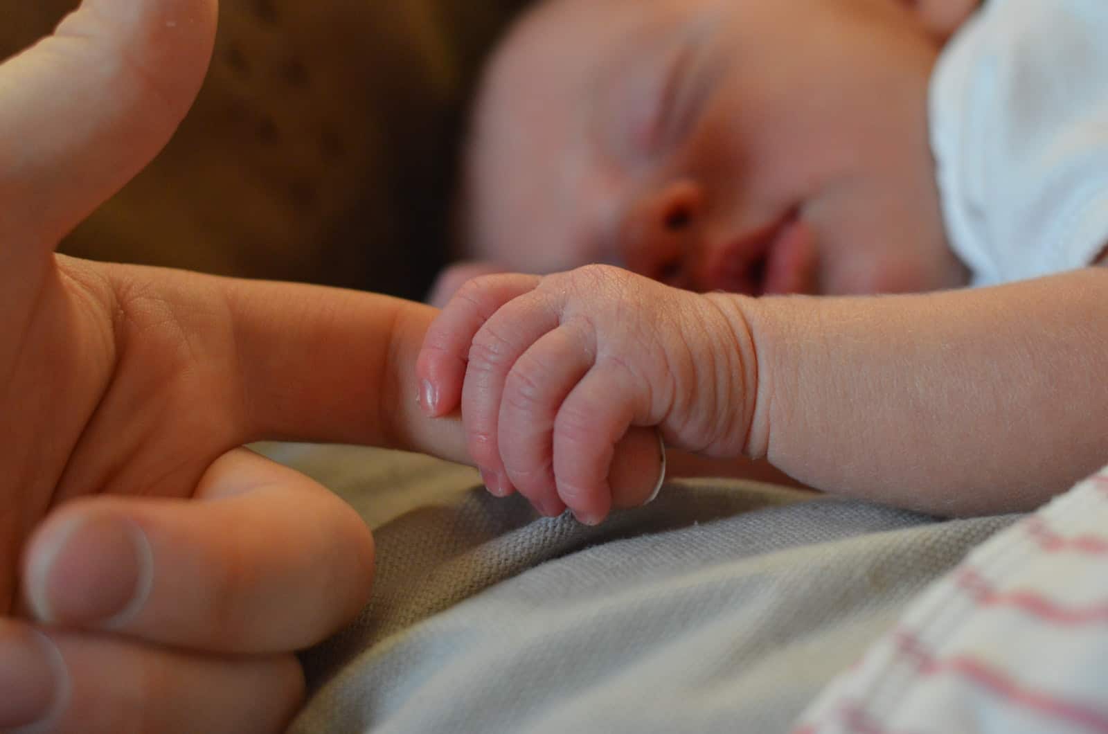 petit bébé tenant le doigt de la mère