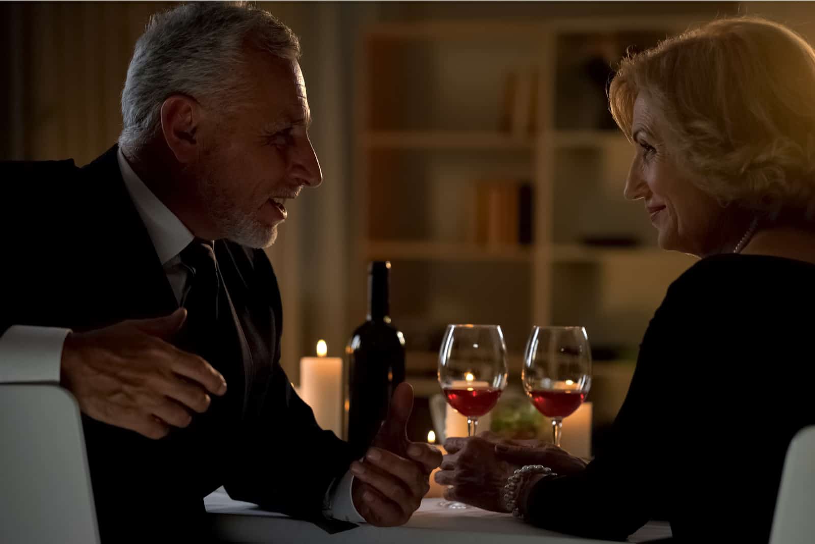 un homme et une femme s'assoient à une table et trinquent avec du vin