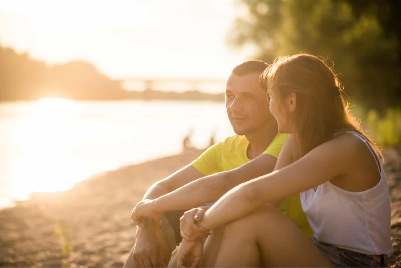 un homme et une femme s'assoient sur la plage et parlent