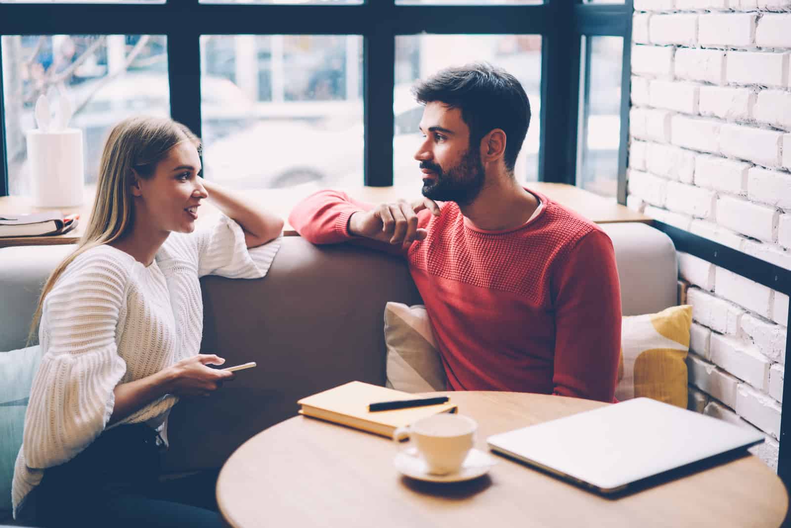 un homme et une femme s'assoient sur une section dans un café et parlent