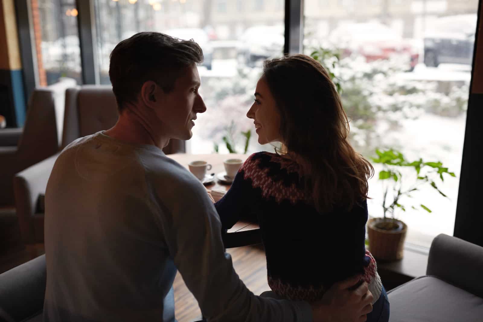 un homme et une femme s'embrassent assis dans un café et parlent