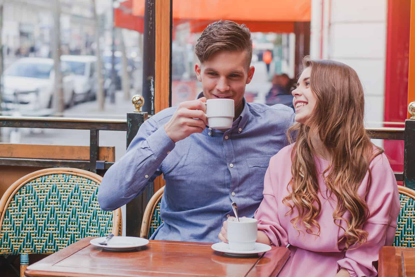 un homme et une femme souriants assis à une table en train de boire du café