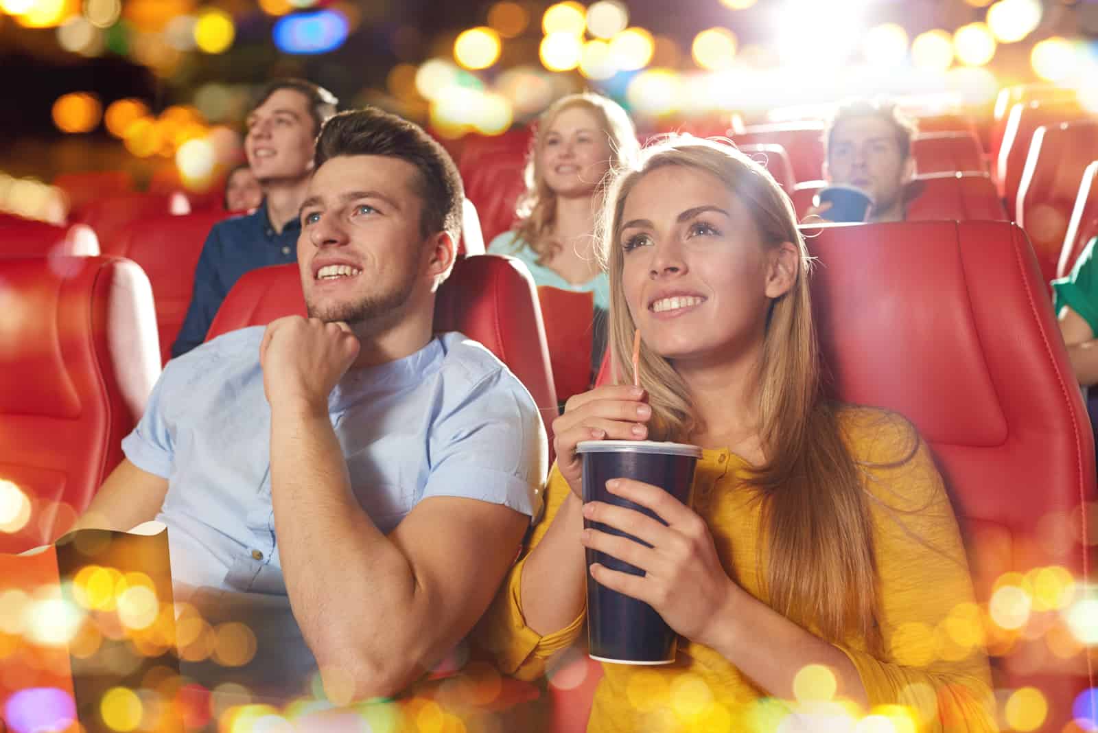 un homme et une femme souriants au cinéma en train de regarder un film
