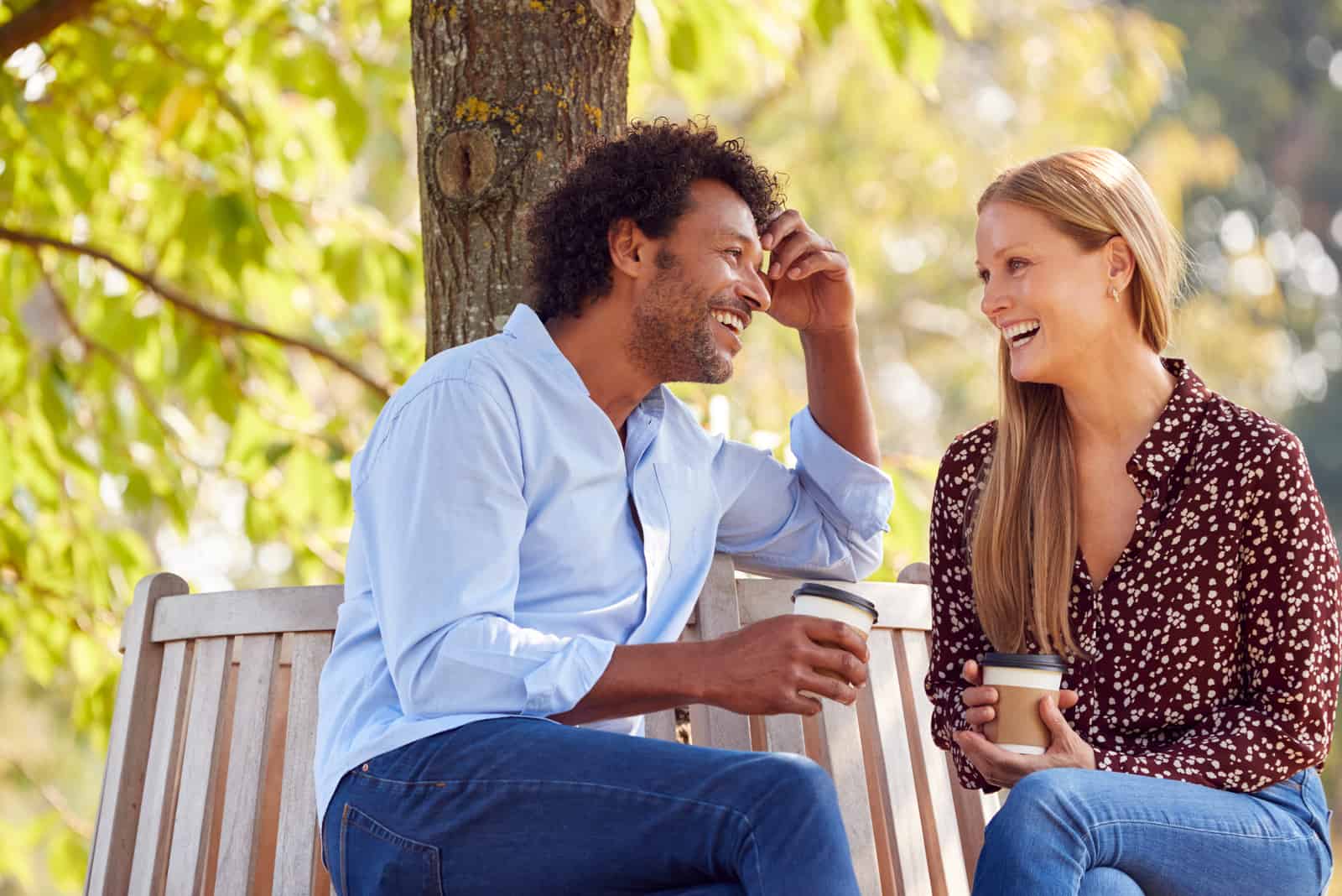 un homme et une femme souriants s'assoient à l'extérieur et parlent