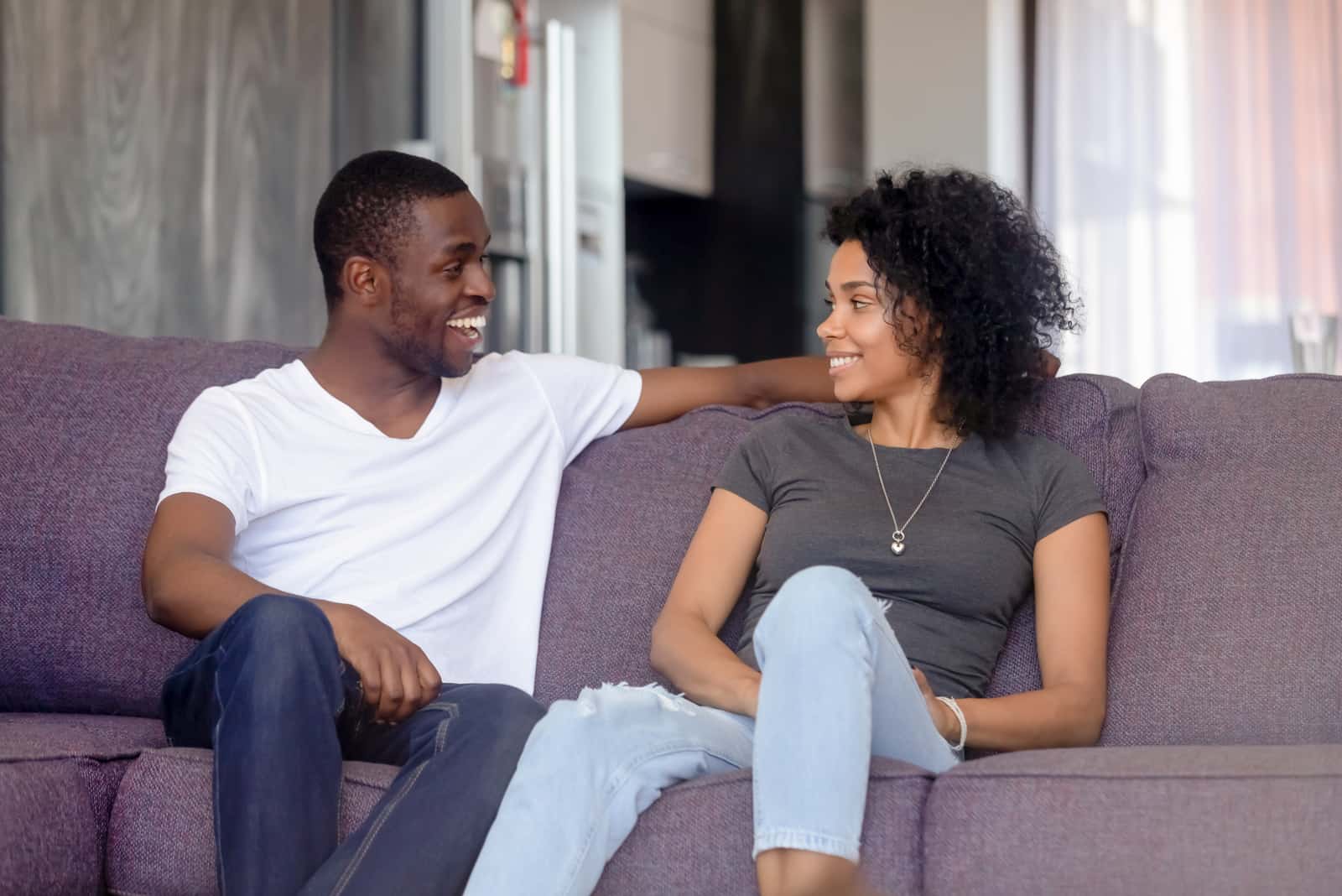 un homme et une femme souriants sur le canapé s'assoient et parlent