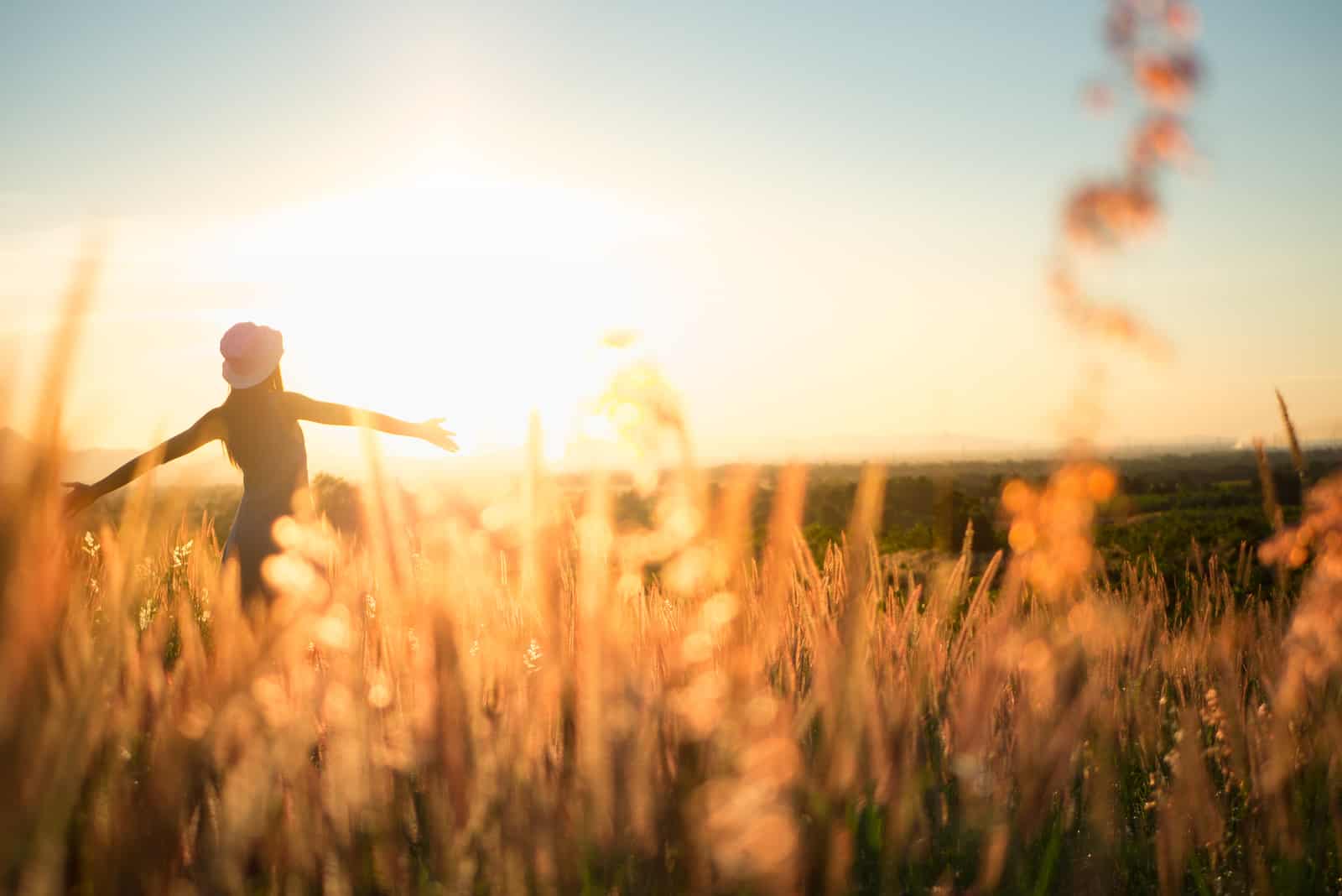 une femme dans un champ de blé se tient les bras tendus