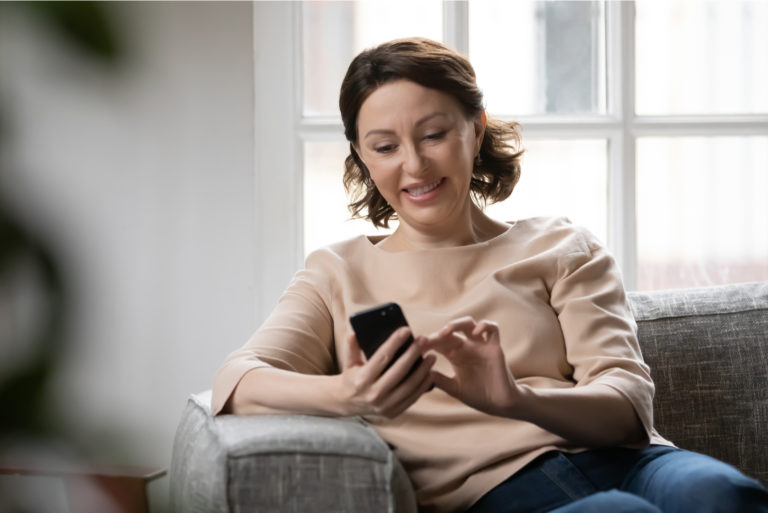 femme heureuse assise sur un canapé envoyant un SMS à sa fille