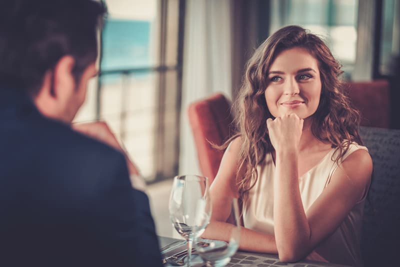 femme souriante regardant l'homme assis avec elle au restaurant