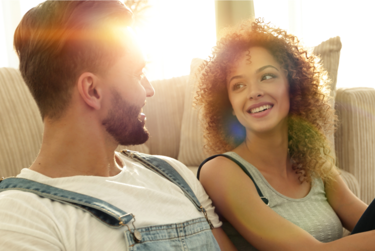un homme et une femme souriants sont assis par terre et parlent