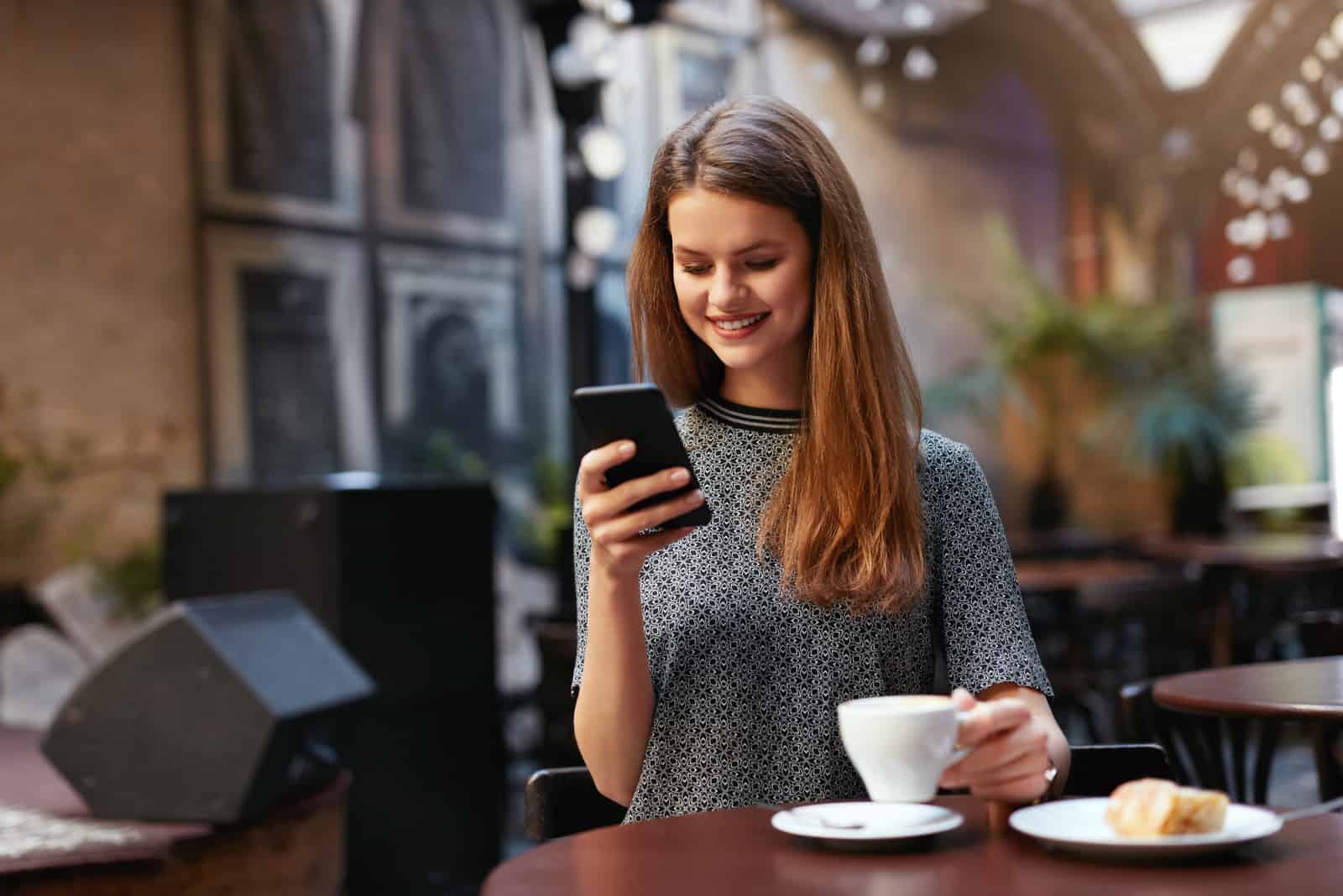 femme assise dans un café et bouton sur le téléphone