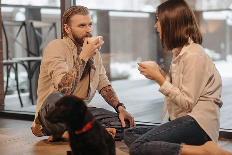 homme et femme assis par terre à la maison en buvant du café