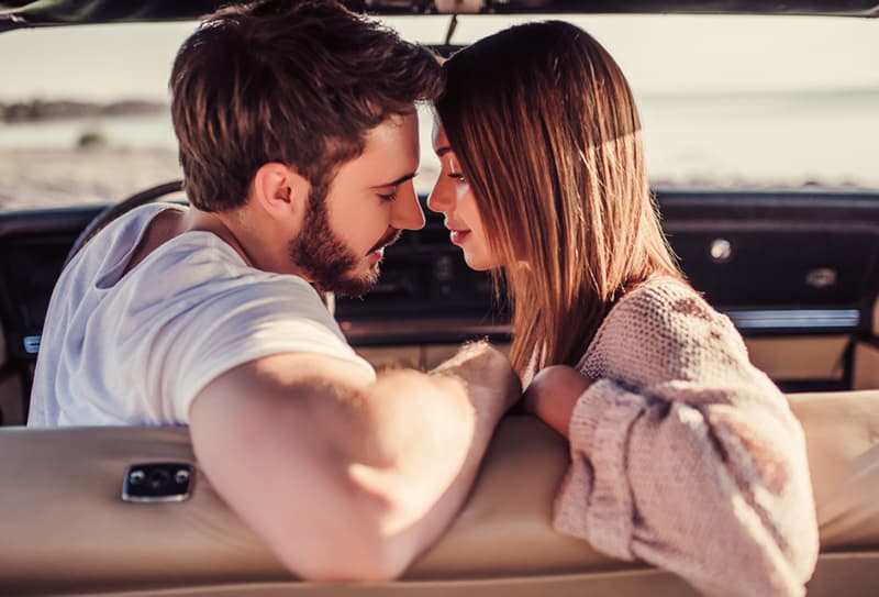homme et femme sur le point de s'embrasser dans la voiture