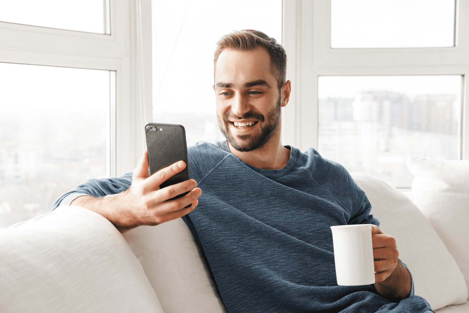 un homme souriant est assis sur le canapé et les boutons du téléphone
