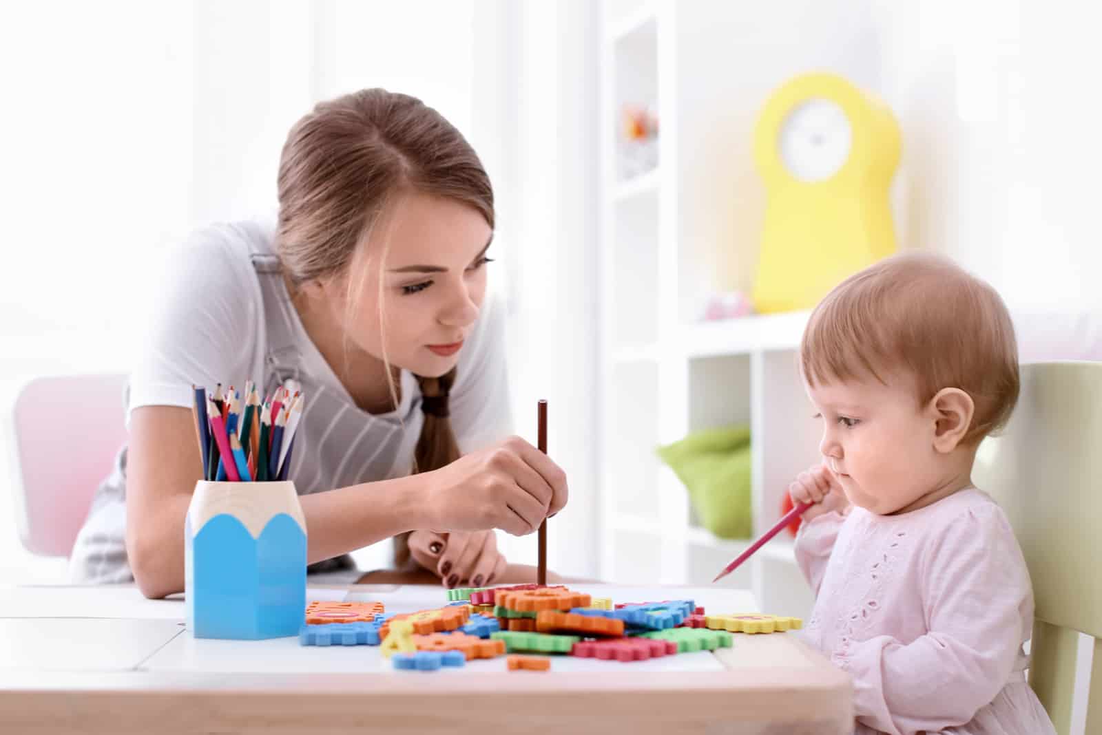 une jeune femme joue avec un petit enfant à une table avec des jouets