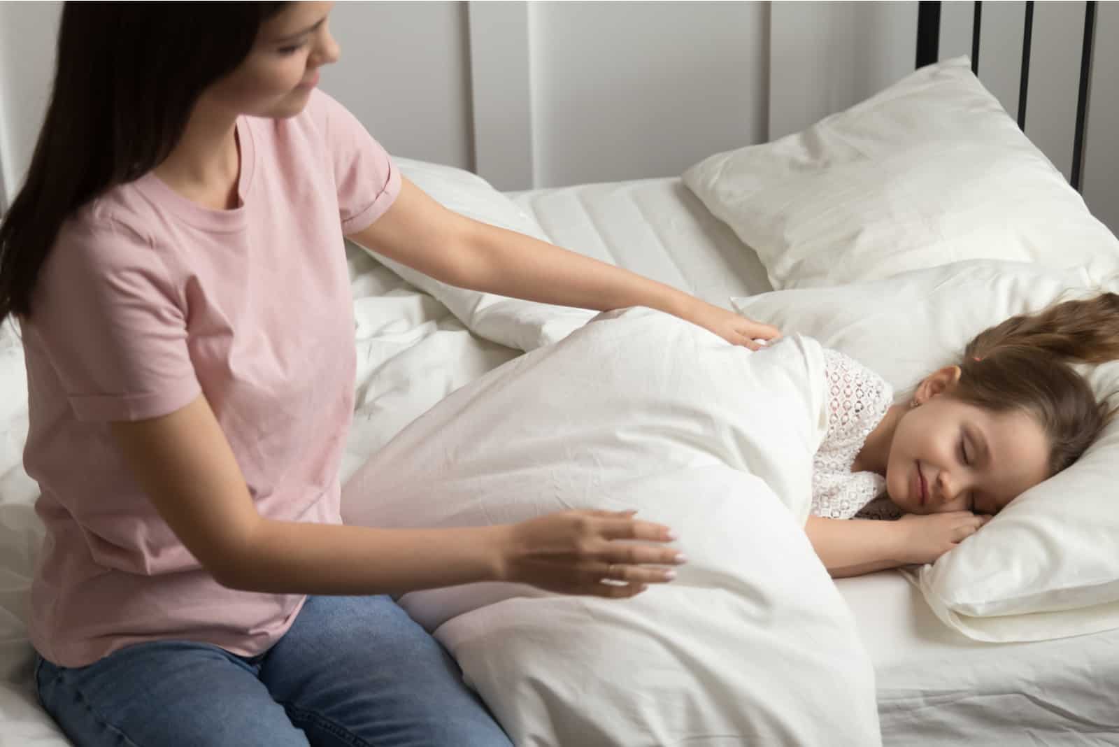une jeune femme prépare un enfant endormi