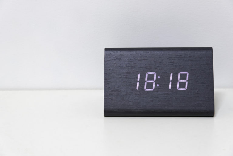 Horloge numérique noire sur fond blanc indiquant l'heure 18:18 minutes