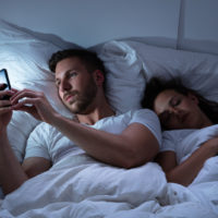 hommes textos au lit pendant que la femme dort
