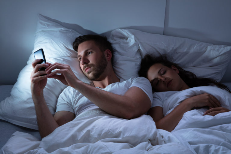 hommes textos au lit pendant que la femme dort