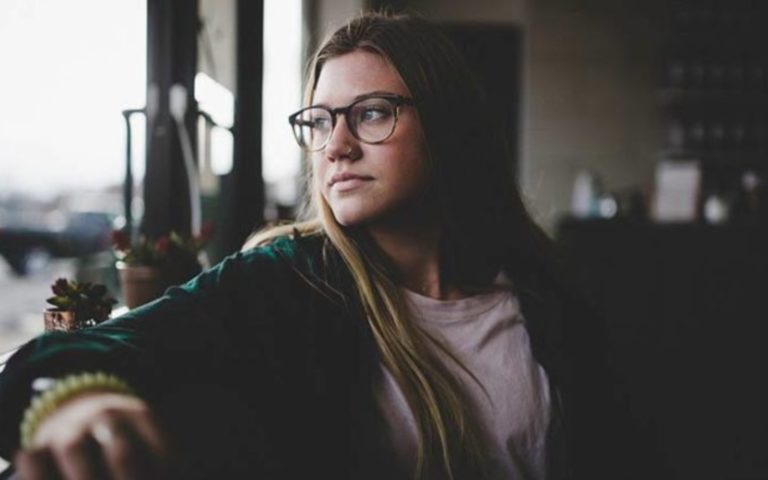 une femme a lunettes regarde par la fenetre