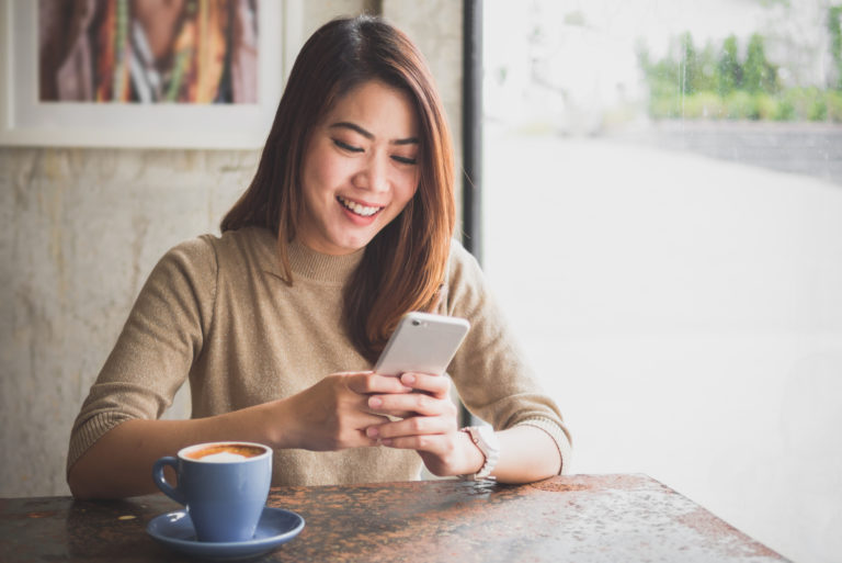une belle femme assise à une table tenant un téléphone à la main