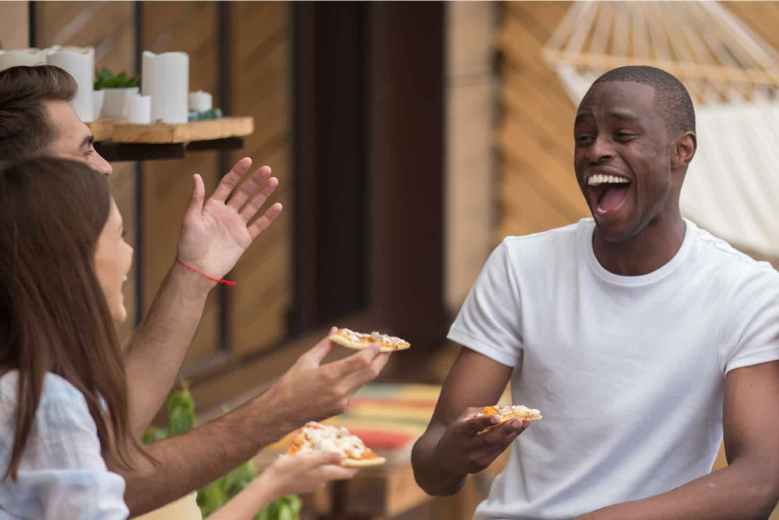 amis souriants mangeant de la pizza et parlant