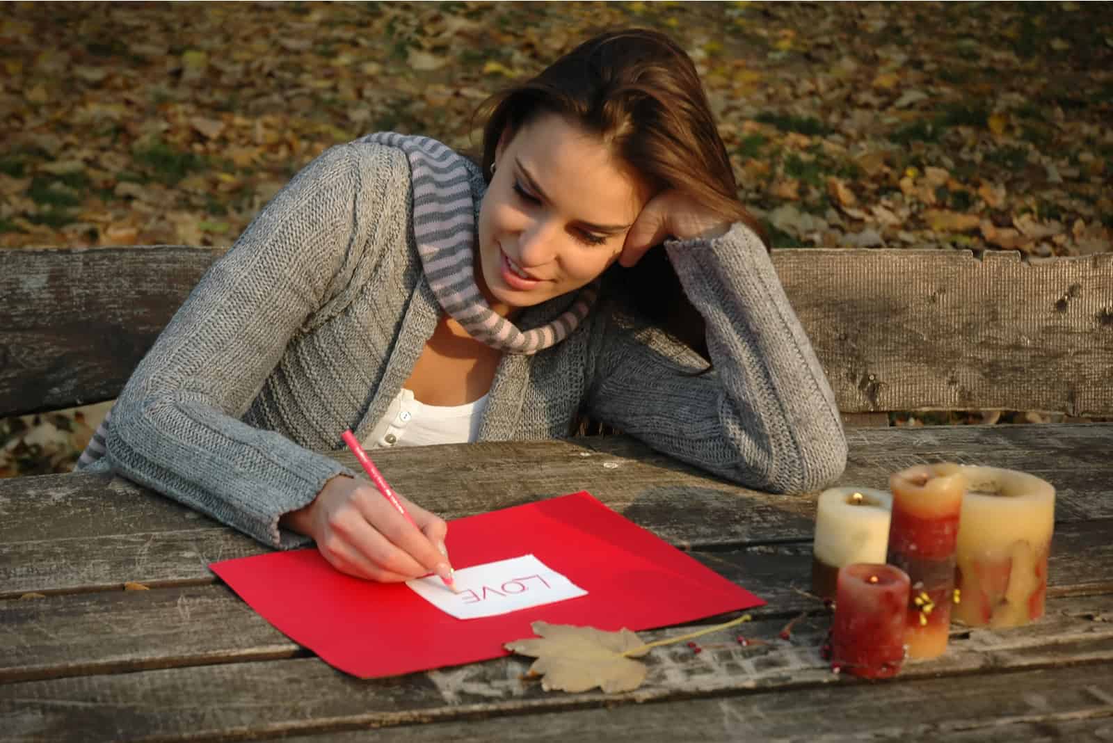 femme assise sur un banc dans un parc écrit une lettre d'amour