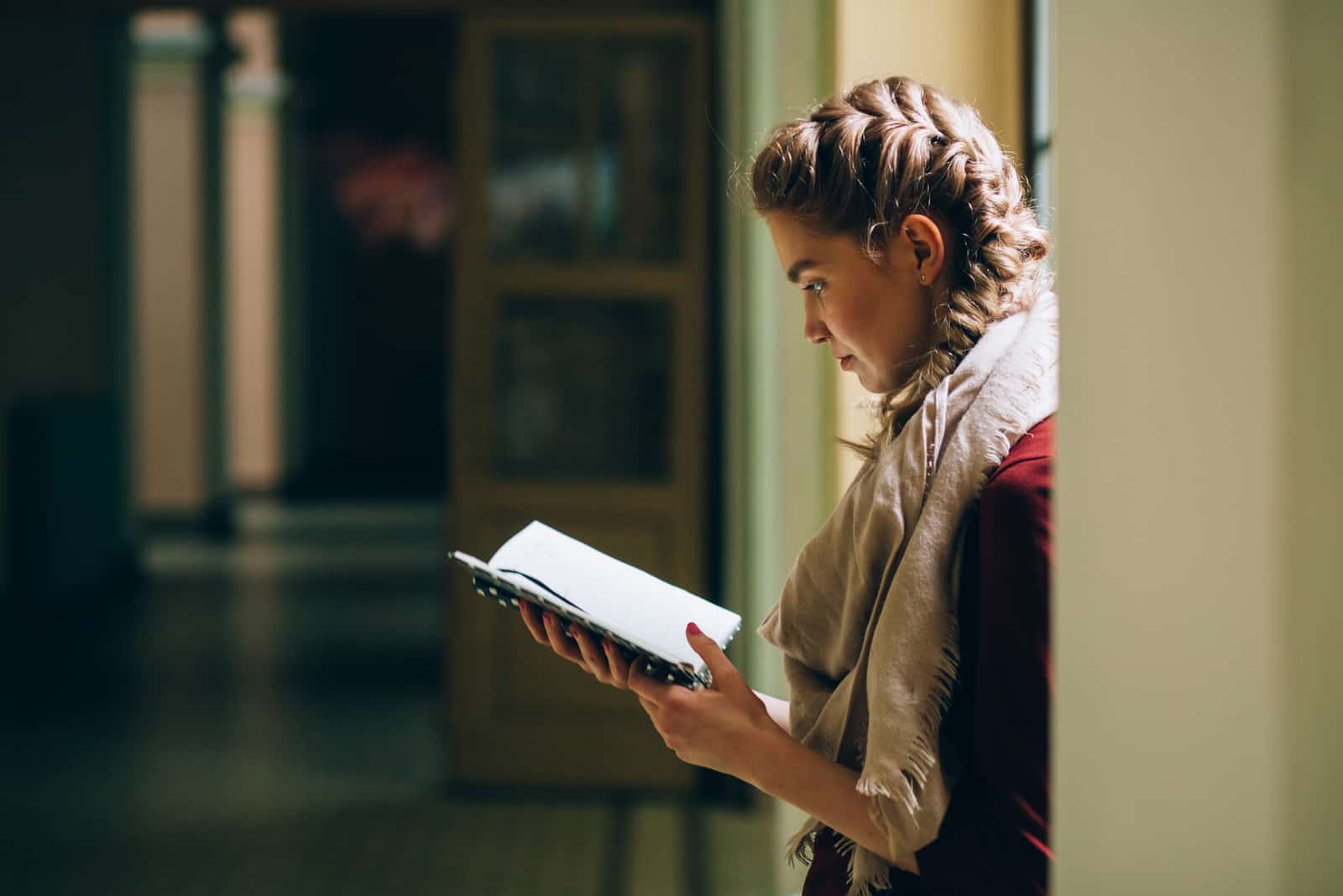 la femme accablée se tient dans le couloir en lisant un livre