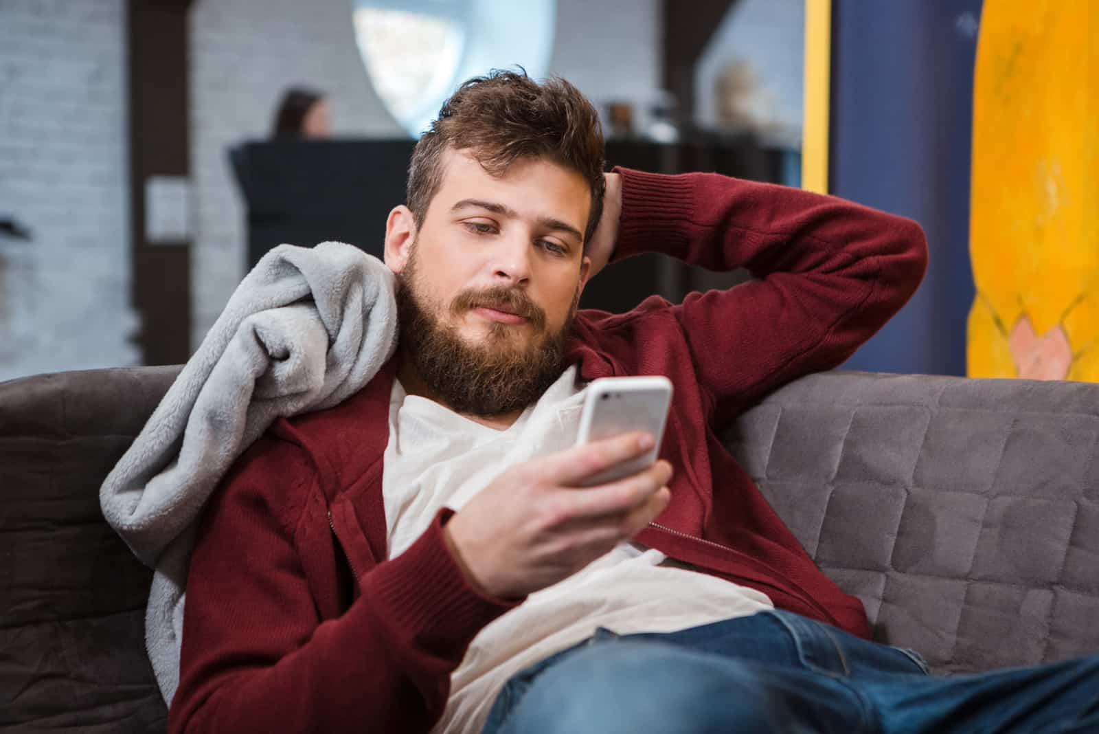 un homme allongé sur un canapé avec un téléphone à la main